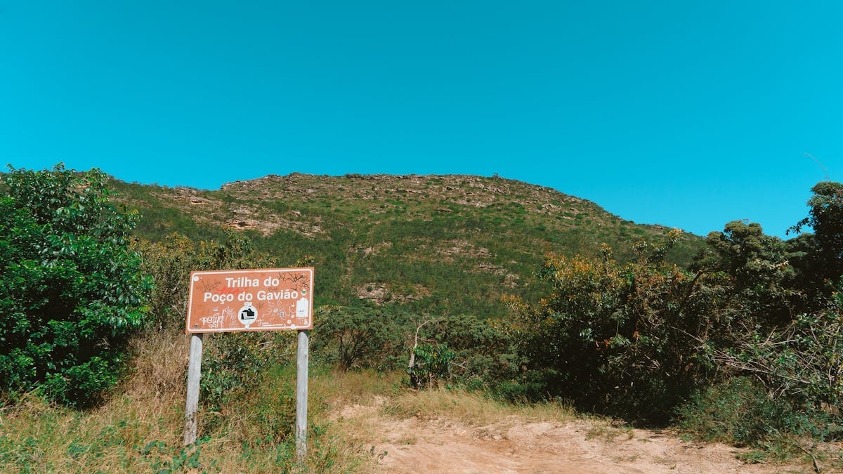 Explore the lush hiking trail of Poço do Gavião under a clear blue sky.